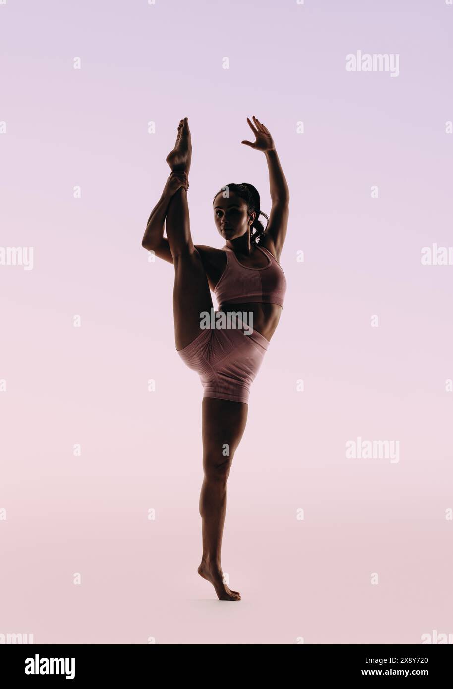 Die FIT-Ballerina zeigt ihr Können und ihre Flexibilität in einer klassischen Tanzroutine. Mit perfektem Gleichgewicht und schlanker Körperhaltung schlägt sie eine einbeinige Pose, di Stockfoto