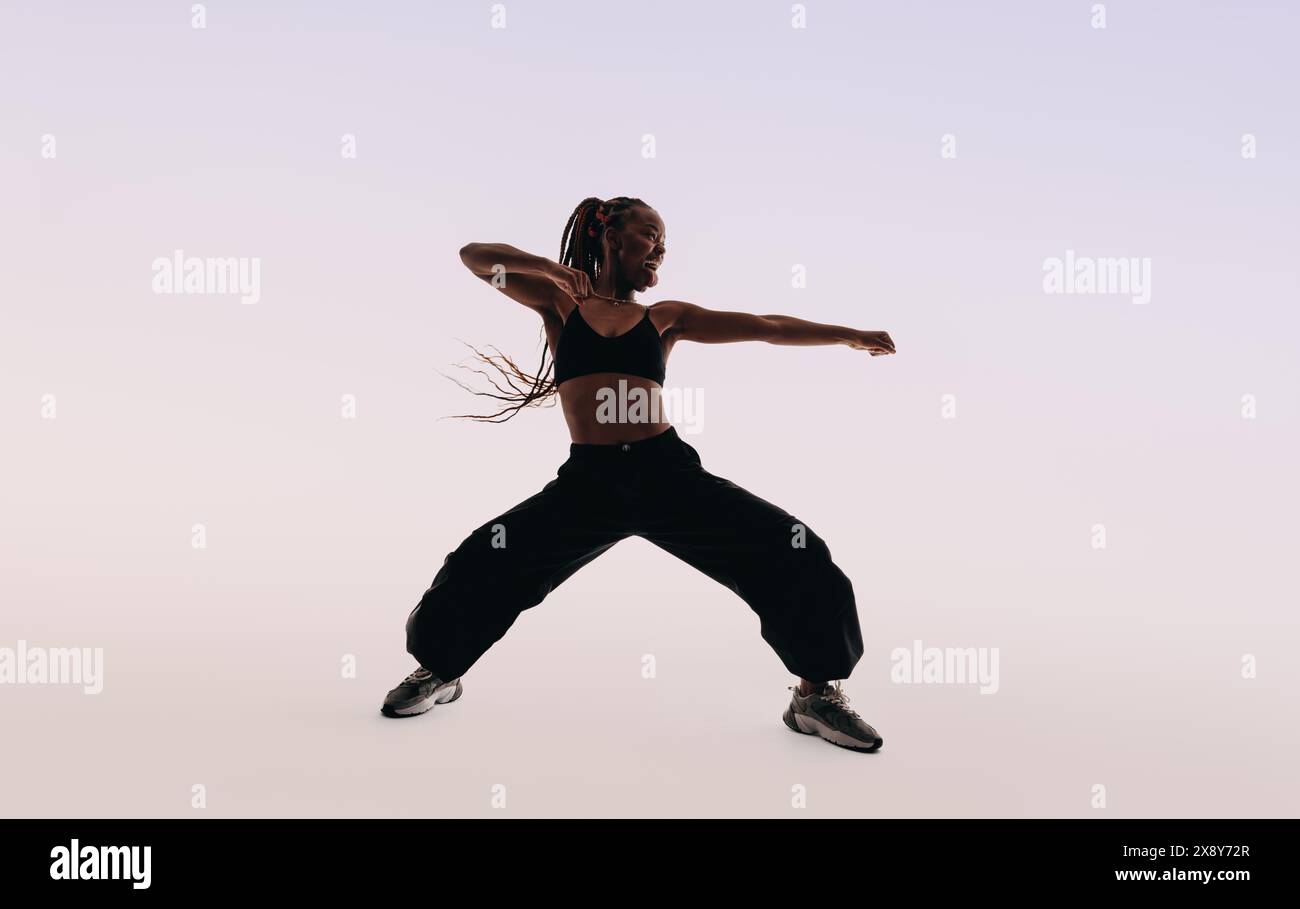 Eine Tänzerin zeigt energiegeladene Tanzbewegungen in einem Studio. Mit ausdrucksstarken Körperbewegungen strahlt sie Fitness und Flexibilität aus. Lustig und lebhaft, sie captain Stockfoto