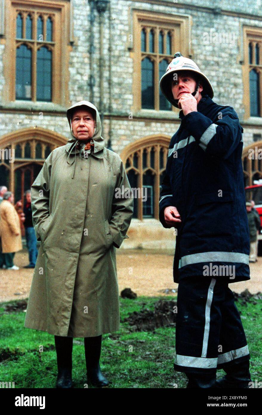 Aktenfoto vom 11/92 von Königin Elisabeth II., die mit einem Feuerwehrmann die Ruinen der Burg Windsor inspiziert. Ausgabedatum: Dienstag, 28. Mai 2024. Stockfoto