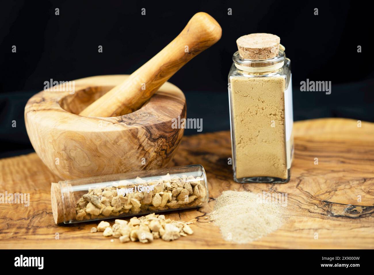 Ingwerknollen, in einer Glasröhre zerkleinert, Ingwerpulver und Moerser Stockfoto