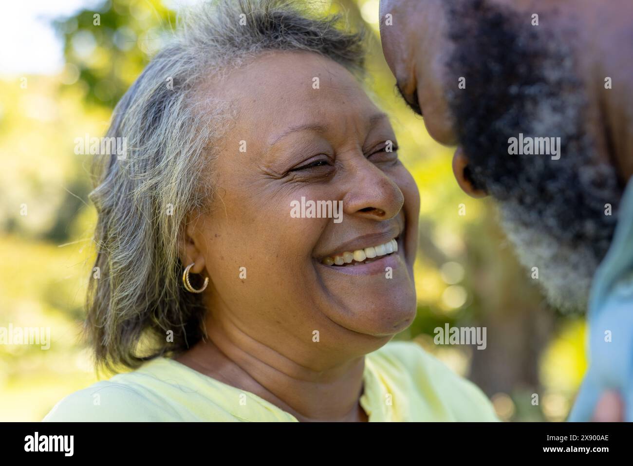 Ein vielseitiges Seniorenpaar, das draußen lacht und den sonnigen Park genießt Stockfoto