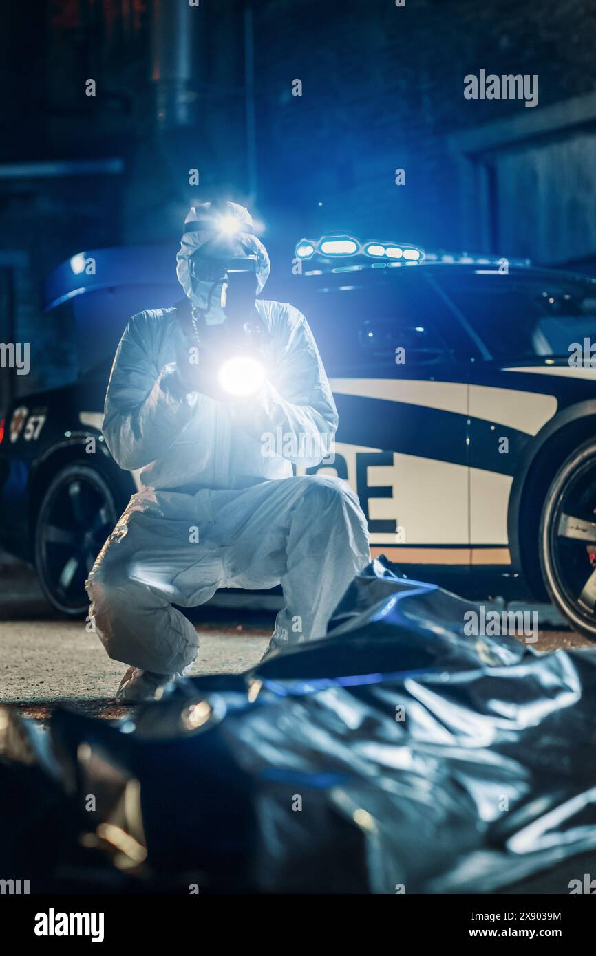 Vertikale Aufnahme: Das Forensik-Team macht Fotos von Beweismitteln und Leiche des Opfers bei einem Tatort in der Nacht. Professioneller Ermittler, der den Fall eines möglichen vorsätzlichen Mordes aufklärt Stockfoto