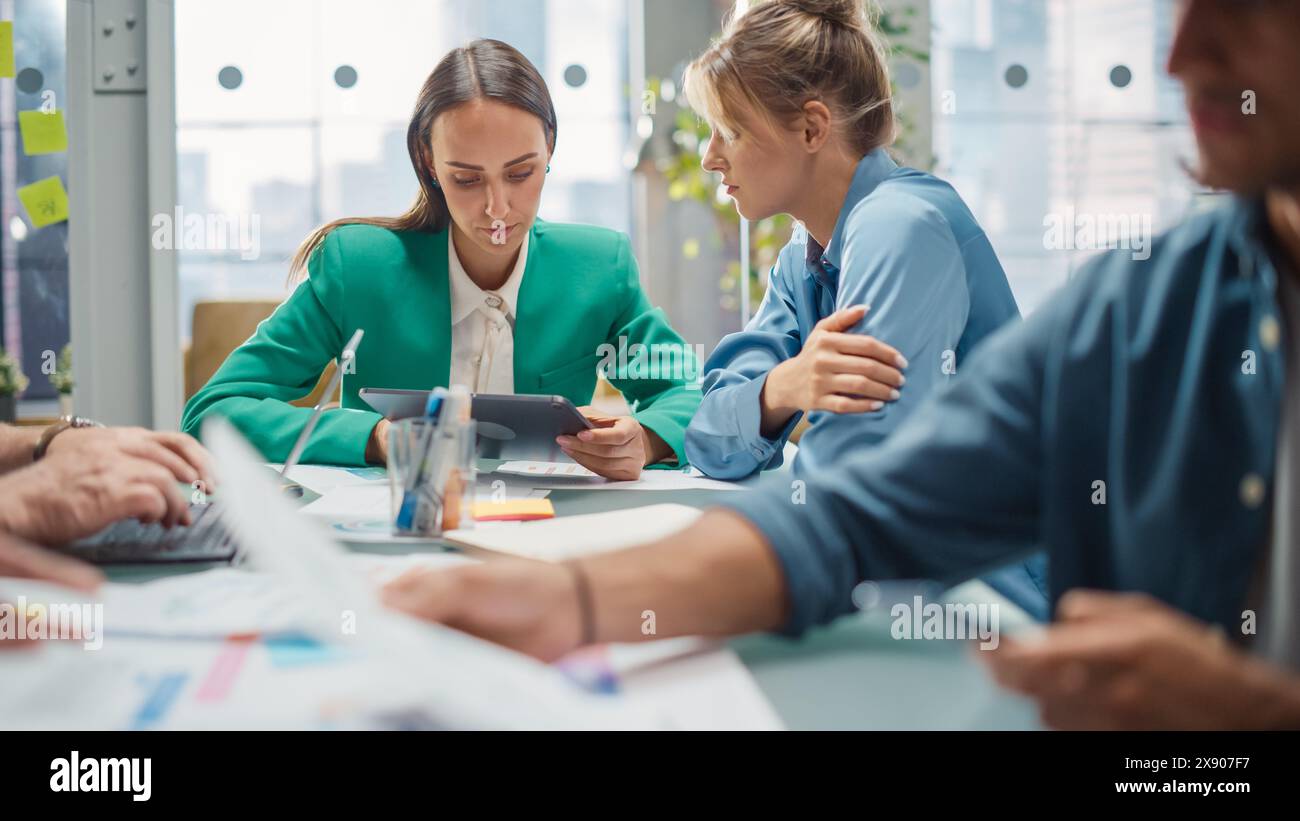 Porträt zweier kreativer Kollegen, die in Office Hub auf ein digitales Tablet zeigen. Weiße Designerin bespricht die Arbeit mit der Assistentin und wählt die Marketingstrategie aus. Arbeitskollegen Stockfoto