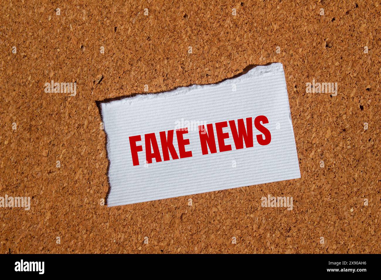 Falsche Nachrichten geschrieben auf zerrissenem weißem Papier mit braunem Hintergrund. Konzeptuelles Fake News-Symbol. Kopierbereich. Stockfoto