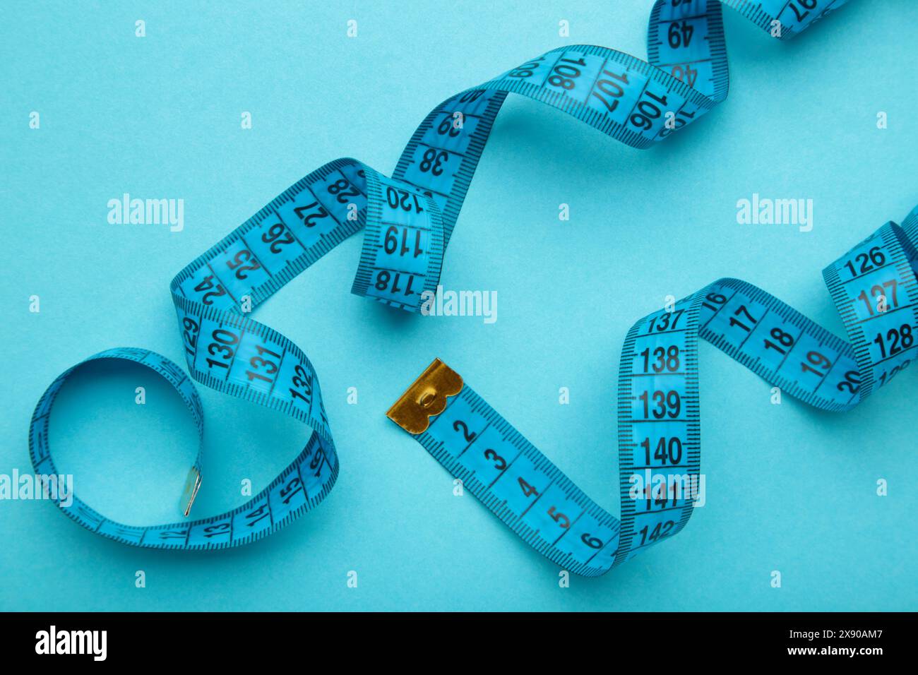 Blaues Kunststoff-Maßband mit metrischer Skala auf blauem Hintergrund. Draufsicht. Diätkonzept Stockfoto