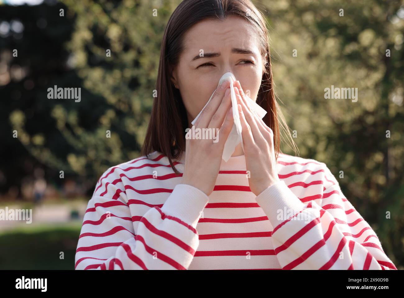 Frau mit Serviette, die draußen saisonale Allergie hat Stockfoto