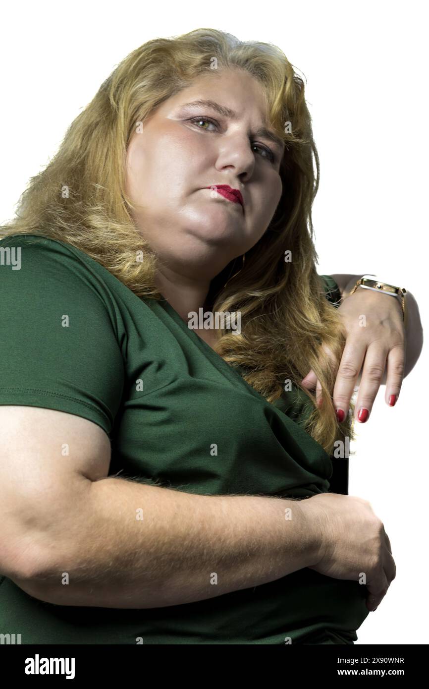 Dieses Foto zeigt eine weiße Frau mittleren Alters mit leichter Fettleibigkeit, die auf einem Stuhl vor einem weißen Hintergrund bequem sitzt. Stockfoto