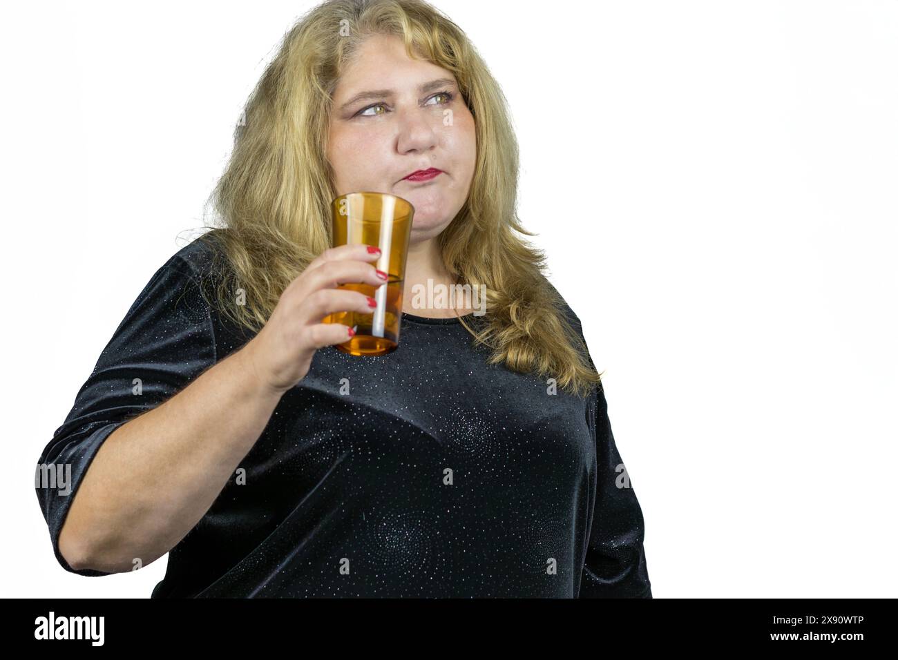 Dieses Bild zeigt ein fesselndes Porträt einer 50-jährigen blonden Kaukasierin mit leuchtend grünen Augen, die ein Glas Wasser in der Hand hält. Ihr Gesicht, klar Stockfoto