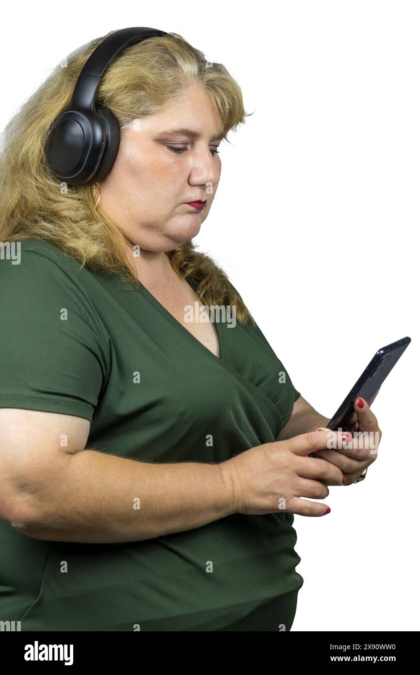 Dieses Foto zeigt eine weiße Frau mittleren Alters, die mit Bluetooth-Kopfhörern über ihr Smartphone in die digitale Welt eingetaucht ist. Stockfoto