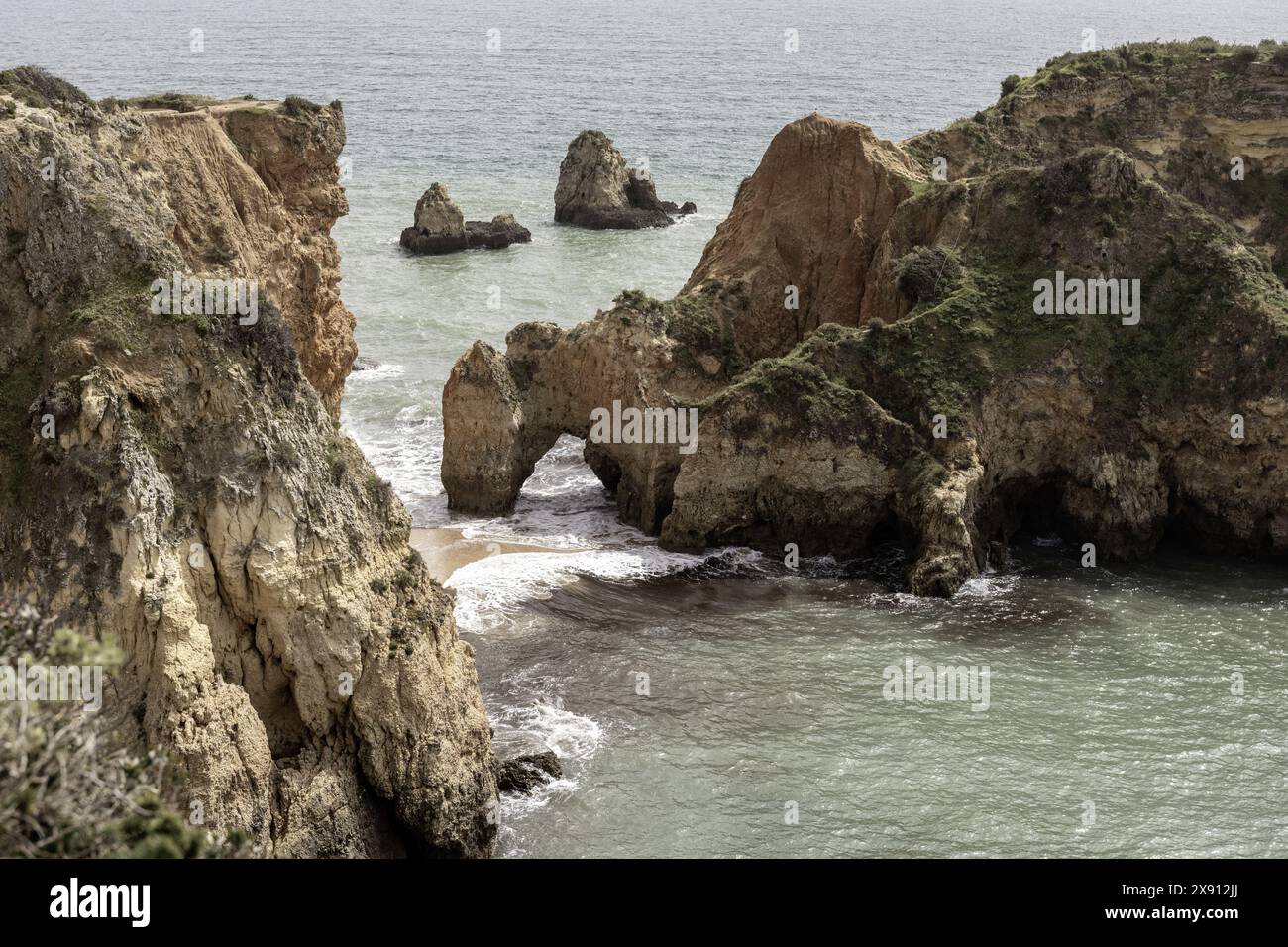 Atemberaubender Blick auf die Felsformationen und Meeresbögen der Küste in Portimao, Portugal. Die zerklüfteten Klippen und die verstreuten Meeresstapel schaffen ein dramatisches Bild Stockfoto