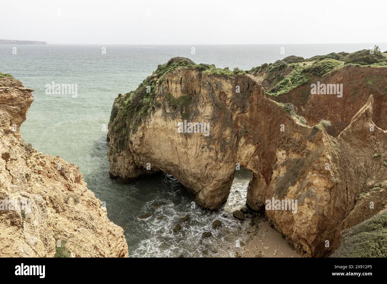 Atemberaubender Blick auf die Felsformationen und Meeresbögen der Küste in Portimao, Portugal. Die zerklüfteten Klippen und die verstreuten Meeresstapel schaffen ein dramatisches Bild Stockfoto