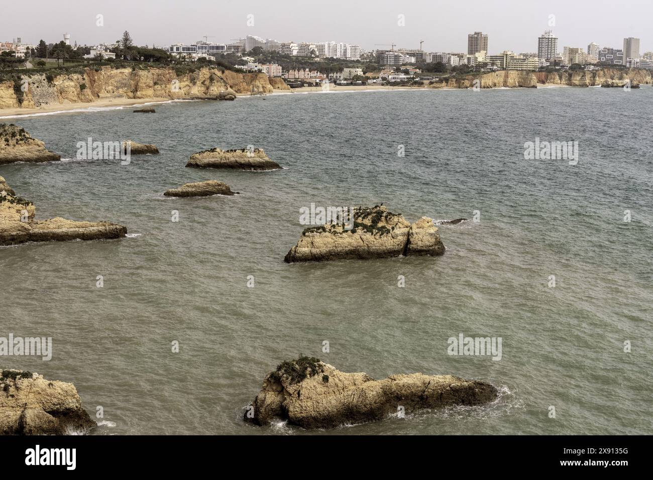 Atemberaubender Blick auf die Felsformationen und Meeresbögen der Küste in Portimao, Portugal. Die zerklüfteten Klippen und die verstreuten Meeresstapel schaffen ein dramatisches Bild Stockfoto