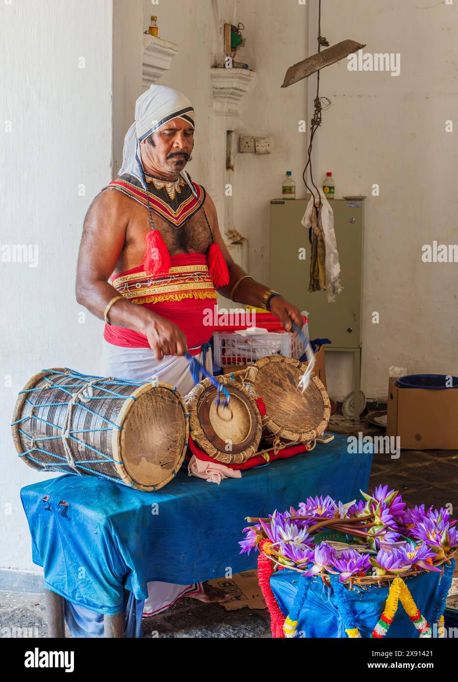 Mann, der zeremonielle Trommeln spielt und die Leute zum Gottesdienst aufruft. Dambulla Höhlentempel, Sri Lanka. Stockfoto