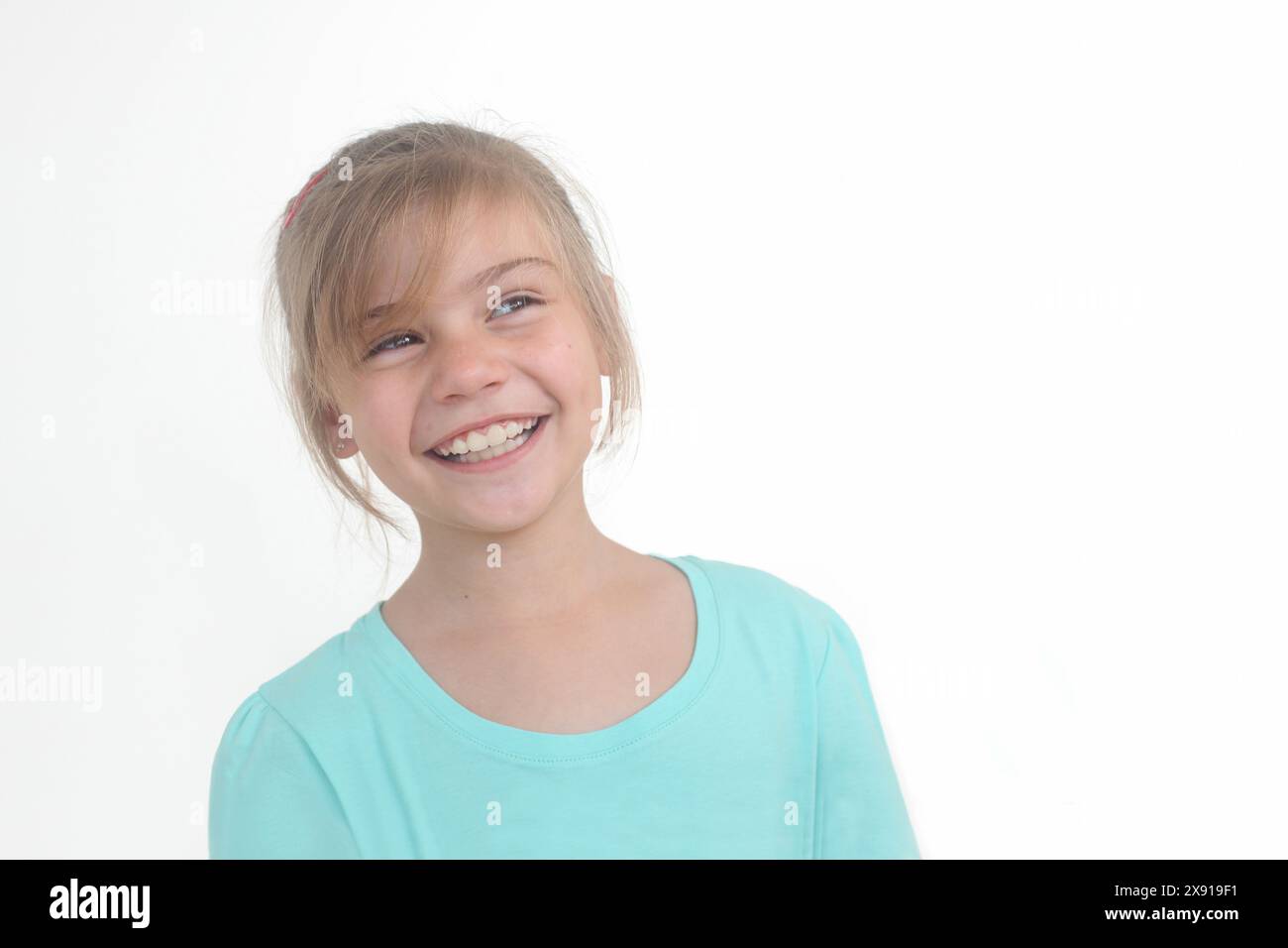 Porträt eines fröhlichen kleinen Mädchens, das seitlich schaut, um Platz auf weißem Hintergrund zu kopieren Stockfoto