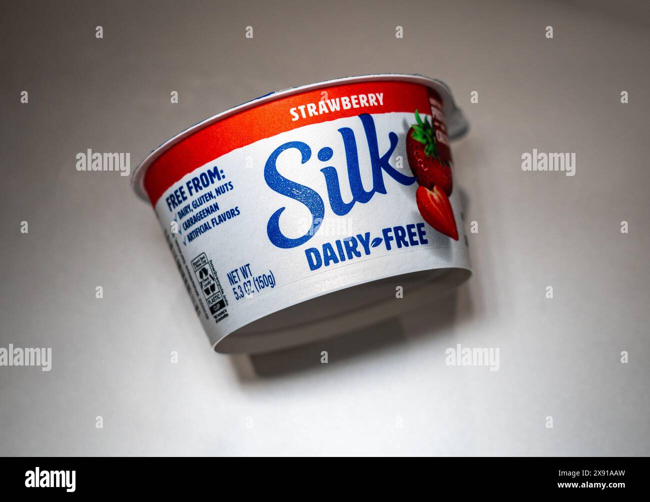 Seidener Joghurt aus Erdbeersoja ohne Milchprodukte auf grauem Hintergrund. Stockfoto