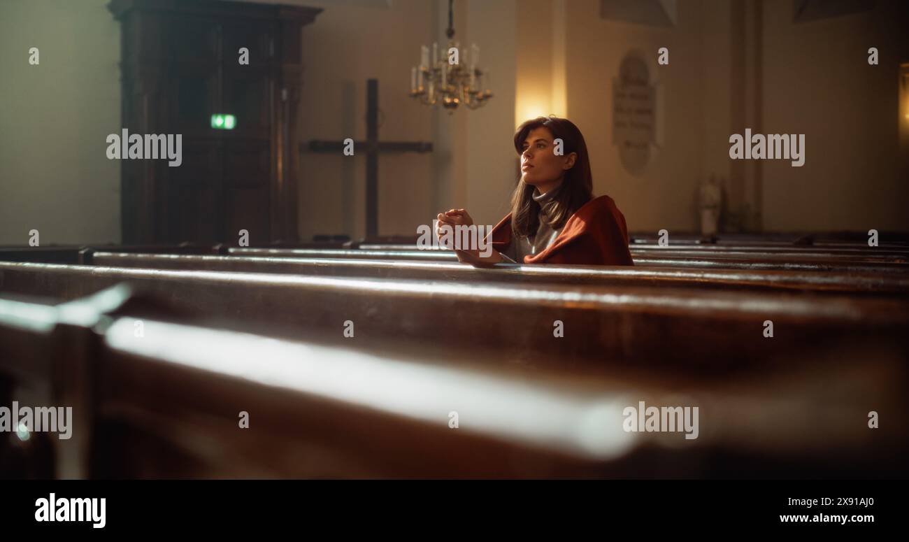 Porträt einer jungen Frau, die in der majestätischen alten Kirche betet. Die Gemeinde fühlt die Verbindung zum Göttlichen. Hoffnung und glaube an Erlösung durch Güte, Freundlichkeit. Kontemplation im Dom Stockfoto