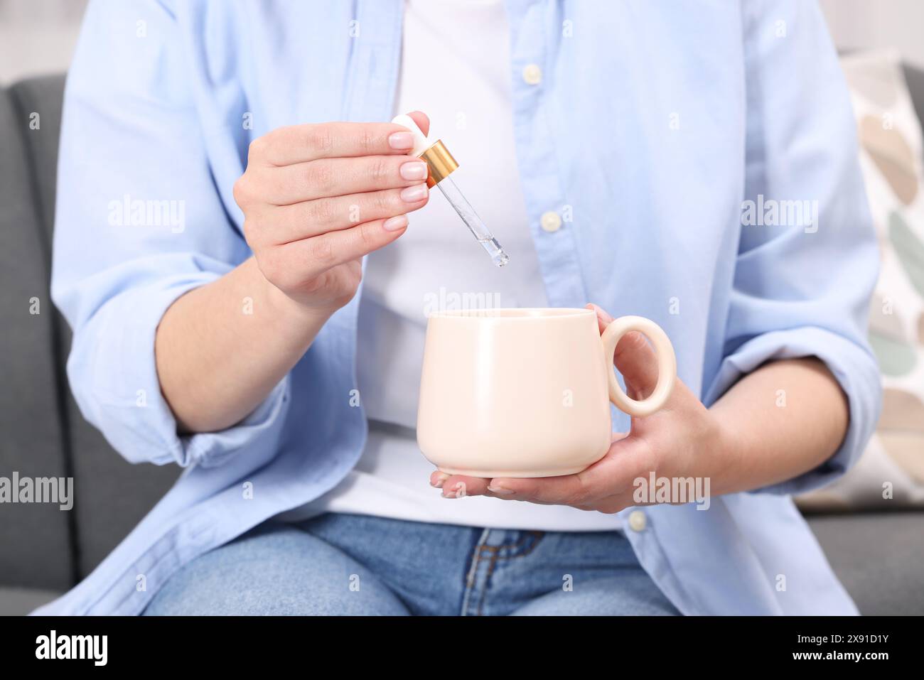 Frau, die drinnen Nahrungsergänzungsmittel in den Becher tropft, Nahaufnahme Stockfoto