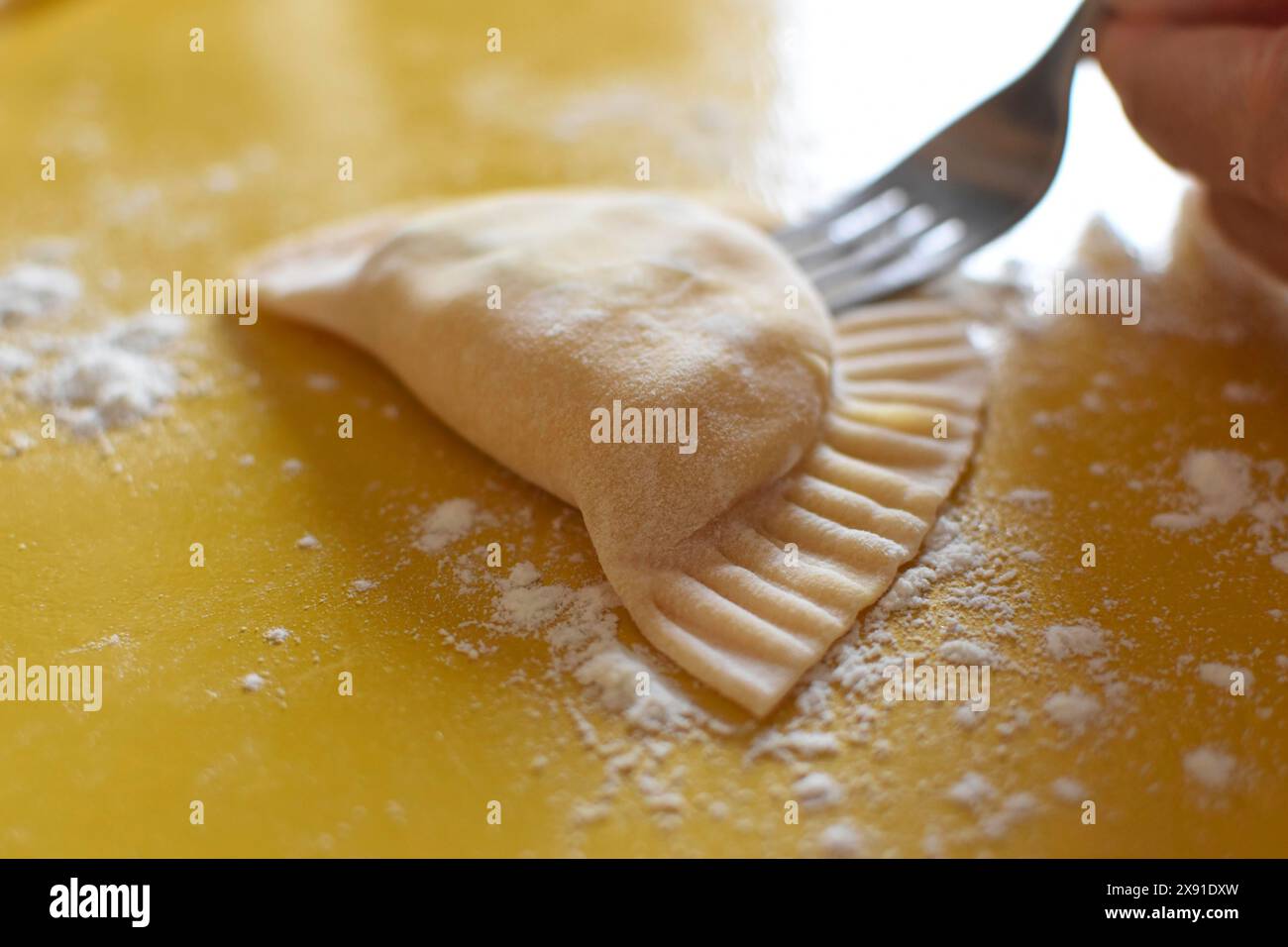 Zubereitung von frischer hausgemachter Pasta Mezzaluna mit Ricotta, Knödel werden mit einer Gabel verschlossen Stockfoto