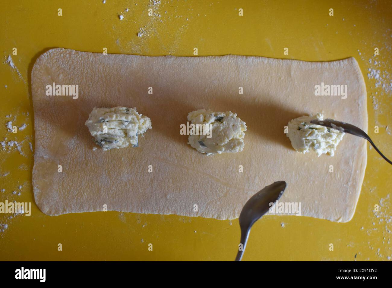 Zubereitung der frischen hausgemachten Pasta Mezzaluna mit Ricotta und Salbei, Füllung wird auf den Teig gelegt Stockfoto