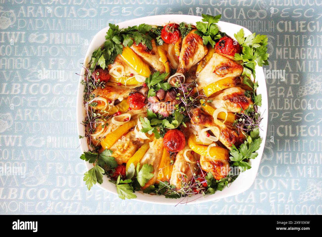 Gebratenes Hähnchen und Paprika in einer weißen Schale mit Kirschtomaten und Petersilie auf einem Hintergrund mit Textdruck Stockfoto