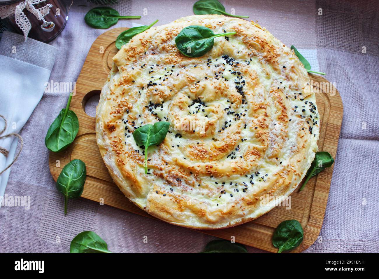 Schwenken Sie Brot mit Samen und Spinatblättern auf einem Holzbrett für eine rustikale und hausgemachte Atmosphäre Stockfoto
