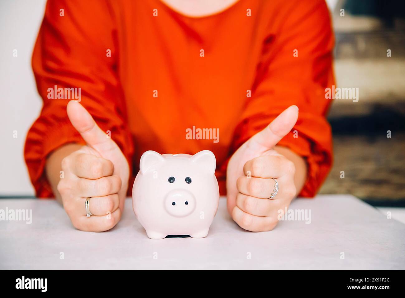 Eine Person in rotem Hemd, die die Daumen hoch neben einer weißen Schweinebank hält Stockfoto