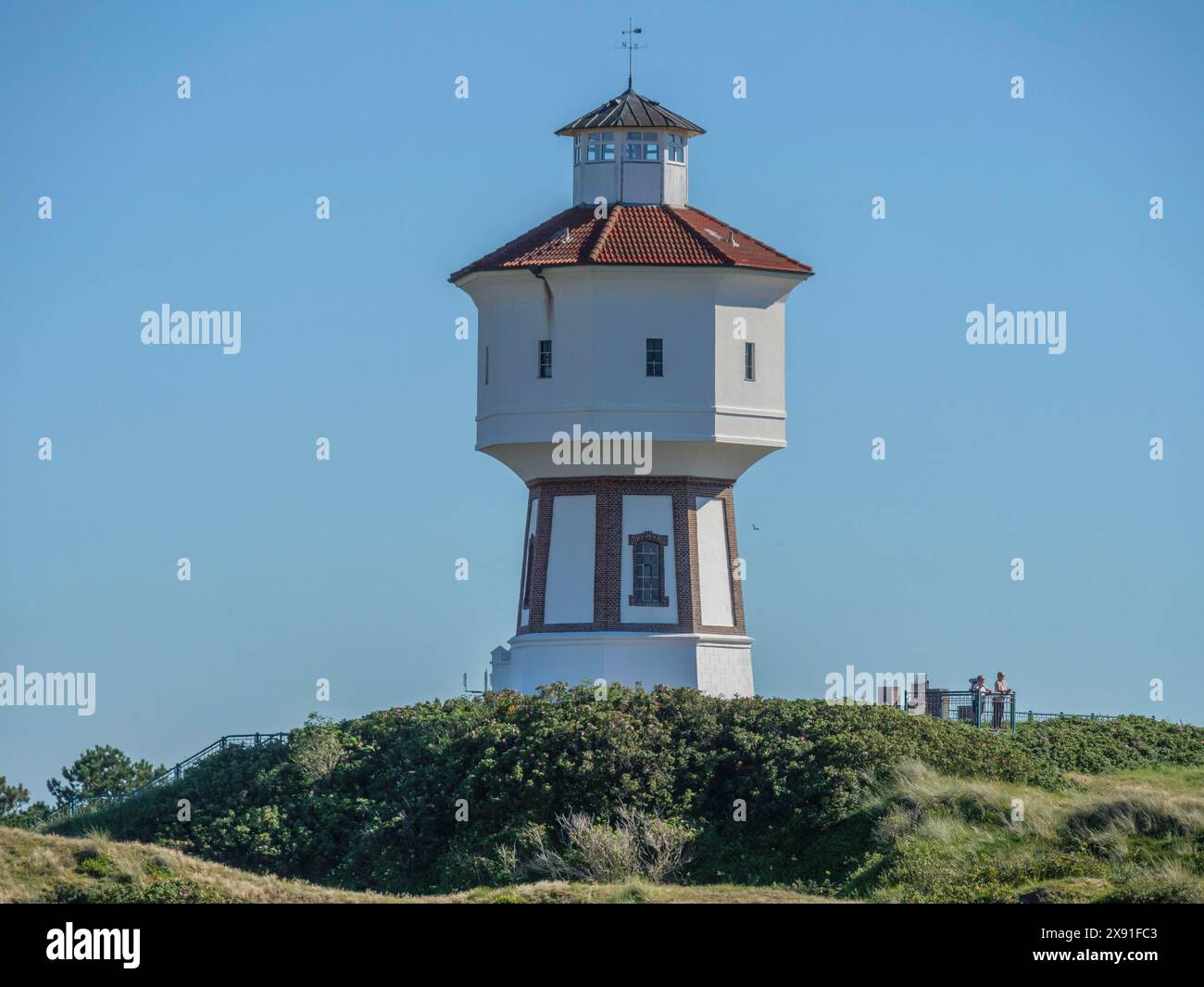 Nahaufnahme eines Leuchtturms auf einem grasbewachsenen Hügel, die Atmosphäre ist ruhig und friedlich, Wasserturm in den Dünen einer Insel, langeoog, deutschland Stockfoto