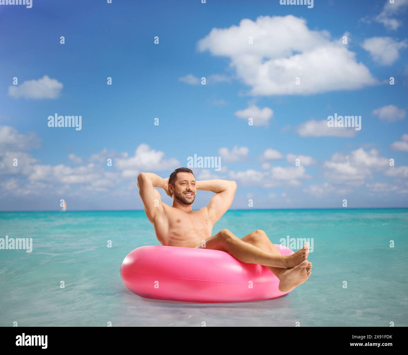 Hübscher junger Mann im Meer, der in einem Schwimmring sitzt Stockfoto