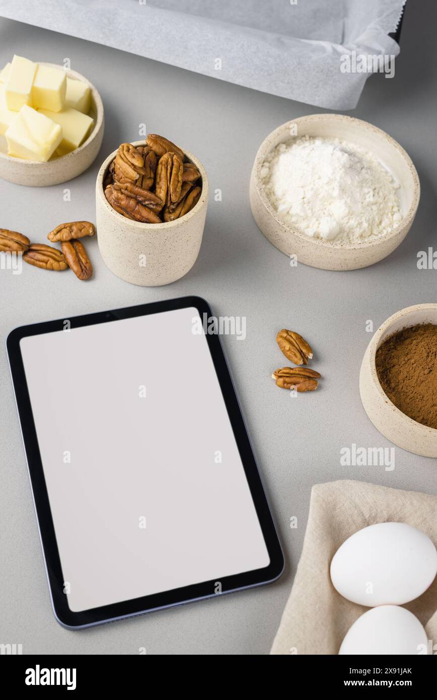 Nahaufnahme von Brownie-Zutaten und Tablette auf grauer Oberfläche in der modernen Küche. Kulinarischer Blog. Stockfoto