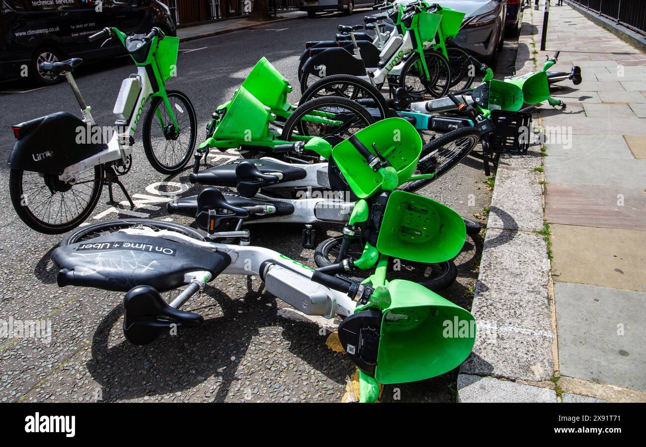 Ein Gewirr grüner und schwarzer Leihfahrräder, verstreut am Straßenrand in London, Großbritannien Stockfoto