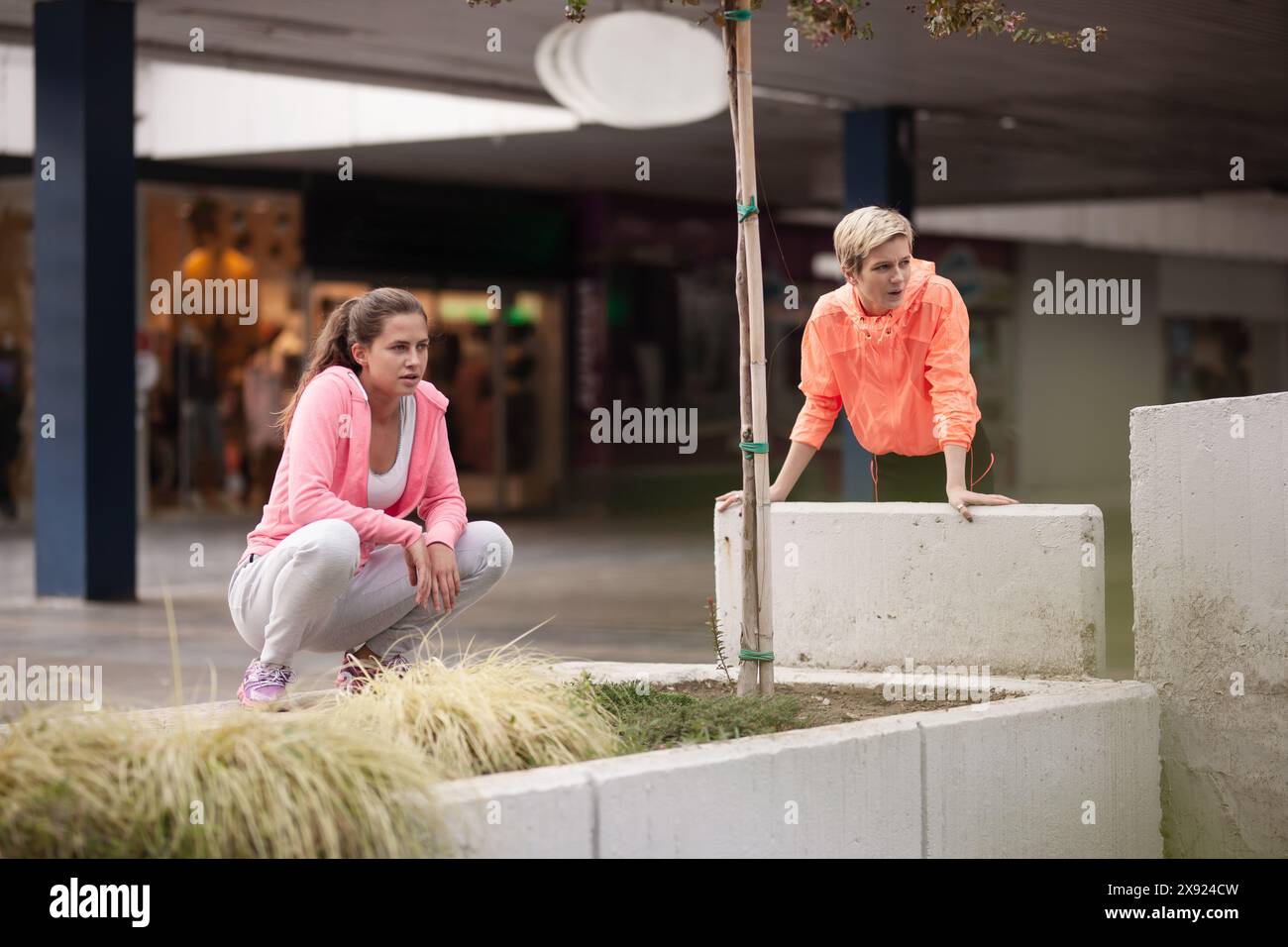 Weibliche Freunde in lässiger sportlicher Kleidung sind auf Entdeckungsreise durch die Stadt aktiv und zeigen Agilität und Teamwork in einer städtischen Umgebung. Stockfoto