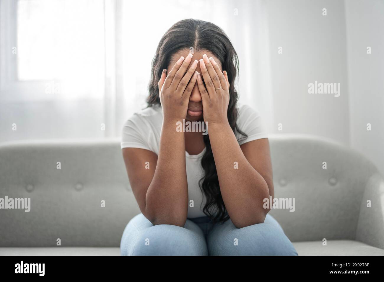 Gestresste miserable schwarze Frau leiden unter Trauer Problem, depressive einsam verärgert afrikanisches Mädchen weinen allein auf dem Sofa Stockfoto