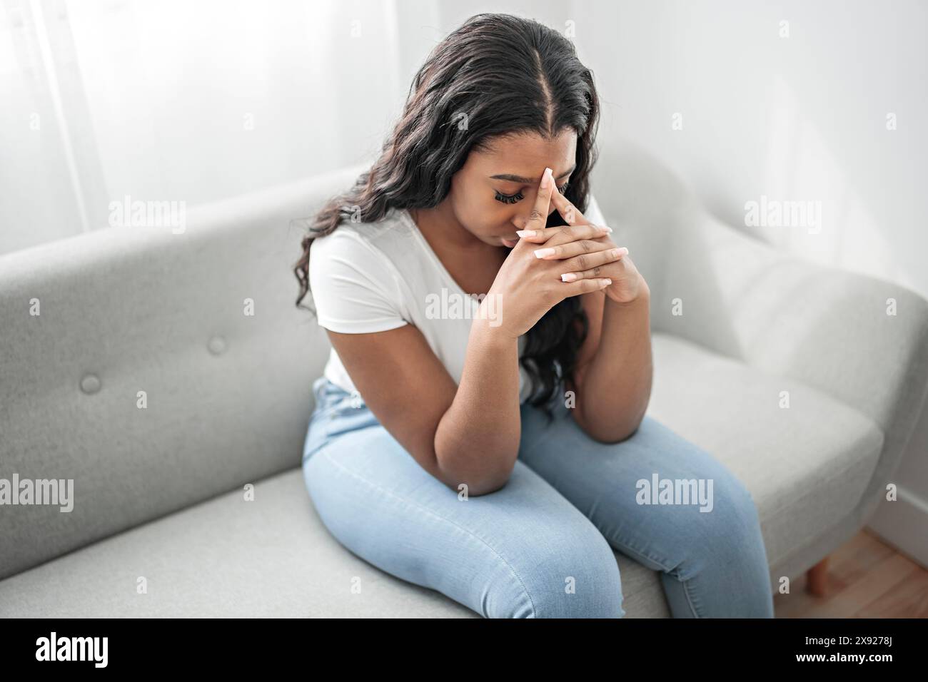 Gestresste miserable schwarze Frau leiden unter Trauer Problem, depressive einsam verärgert afrikanisches Mädchen weinen allein auf dem Sofa Stockfoto