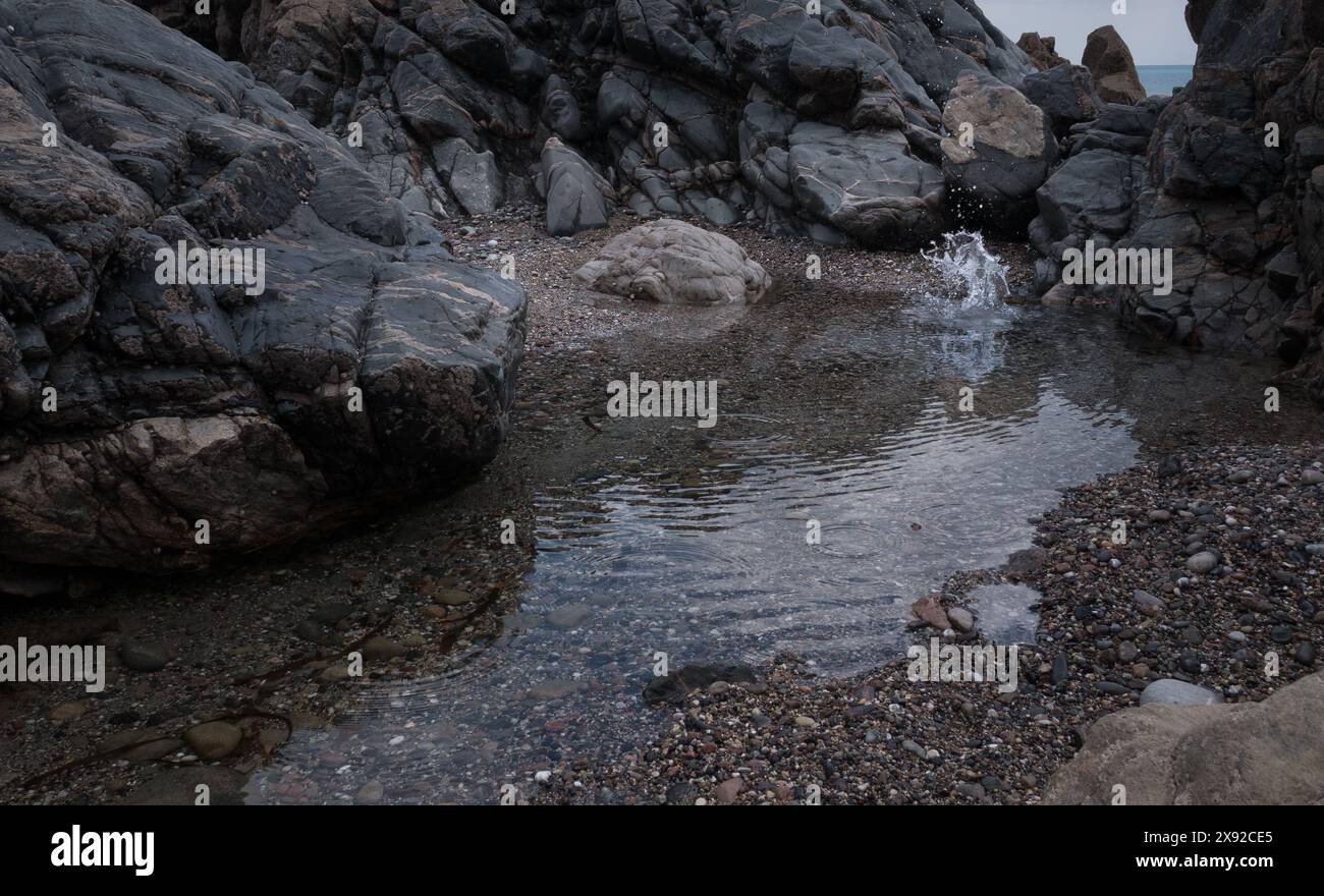Gezeitenfelsenbecken in Kennack Sands, Cornwall. Ein Steinspritzer im Pool. Spritzer machen. Stockfoto