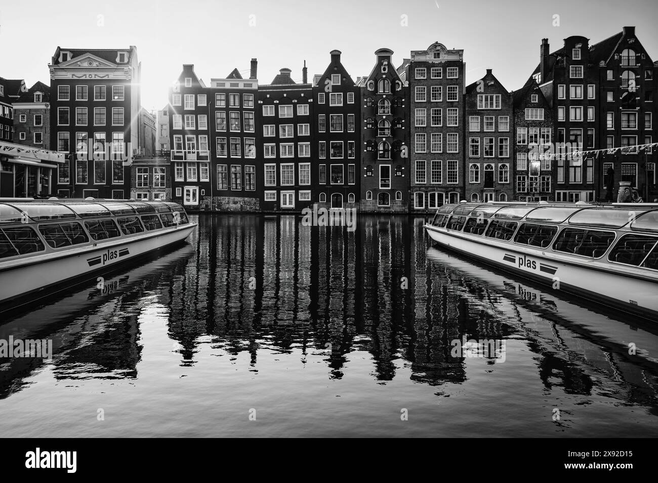 Niederlande, Amsterdam - 07. April 2024: Architektur von Amsterdam, historische Apartmenthäuser mit Reflexionen auf dem Wasser und Boote bereit für eine Kanaltour Stockfoto