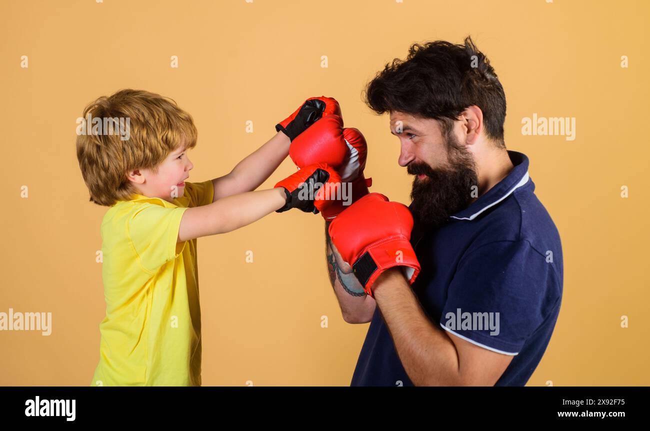 Kinderboxer mit Trainer beim Boxtraining. Kleiner Sohn beim Boxen mit Vater im Fitnessstudio. Kind und Trainer im Boxring. Junge und Trainer im Boxen Stockfoto