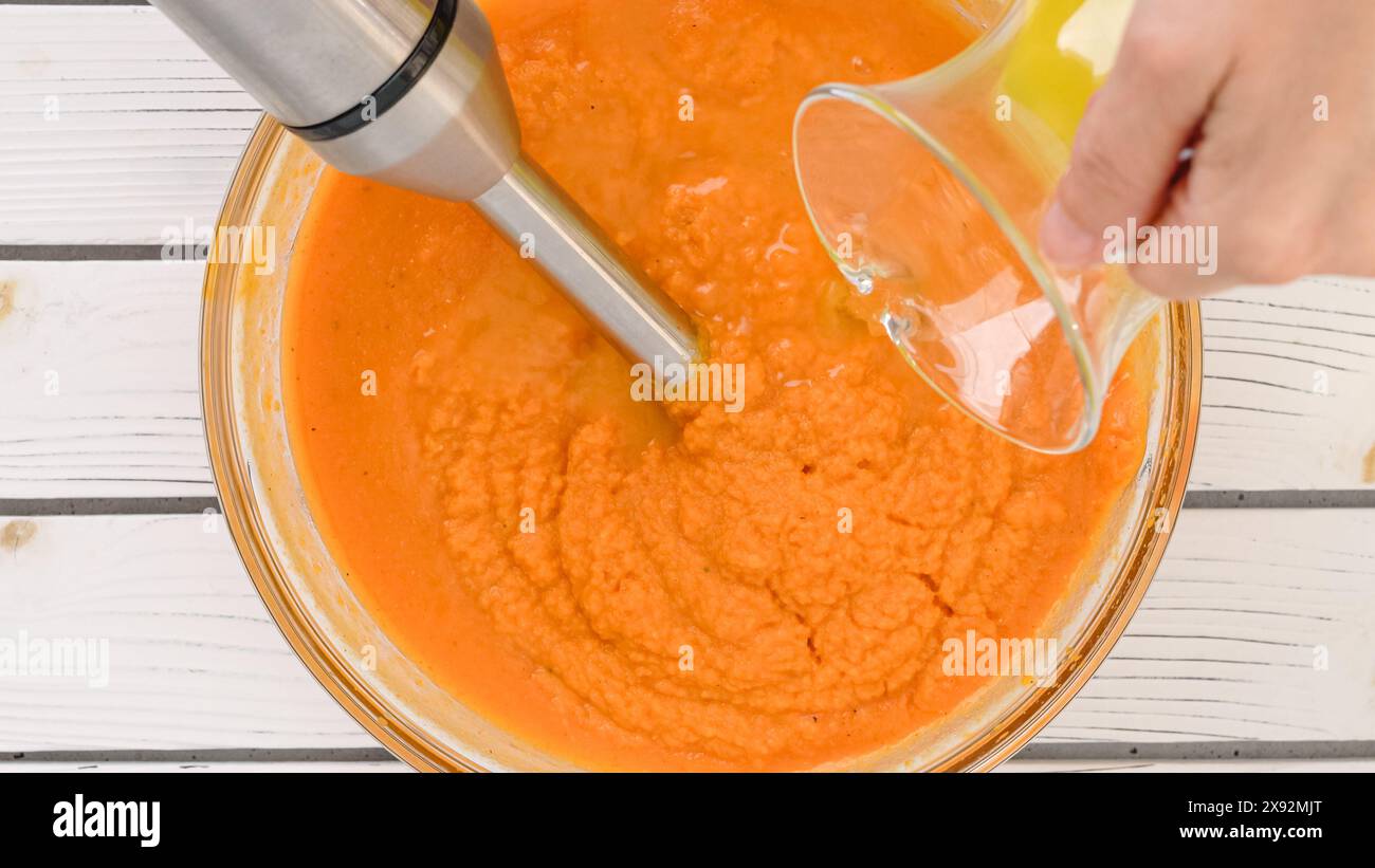 Rezept für geröstete Butternusskürbis-Suppe, Zubereitungsprozess. Geröstetes Gemüse zu einem Püree mischen, Gemüsebrühe in einer Schüssel hinzufügen, Nahansicht Stockfoto