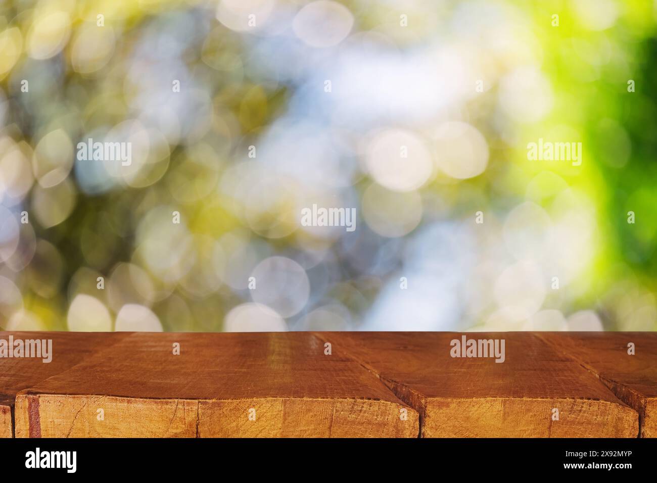 Rustikaler hölzerner Präsentationstisch mit grünem Bokeh auf dem Hintergrund, Platz für Produkt, Sommervorlage Stockfoto