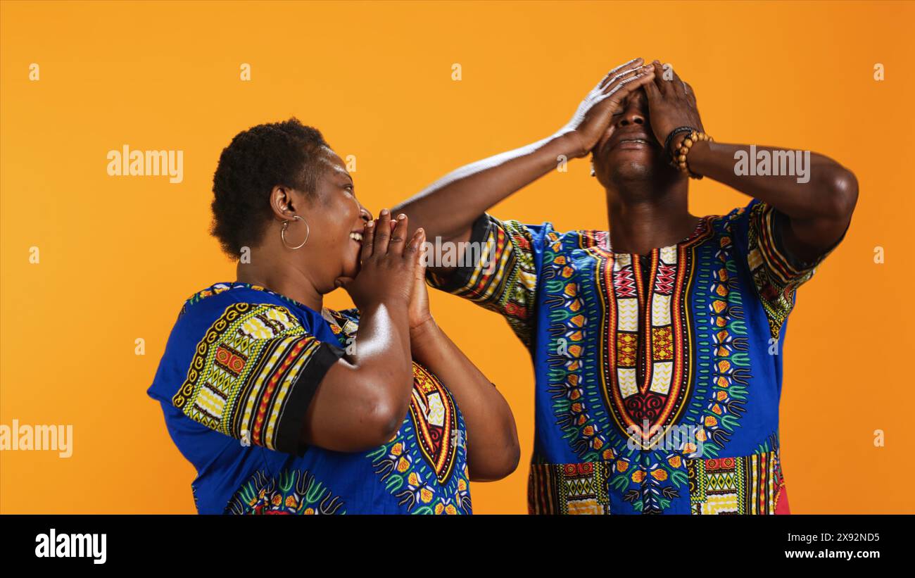 Fröhliches afroamerikanisches Paar lacht über die Sache im Studio, hat Spaß mit Witzen und amüsiert über den Hintergrund. Verheiratete ethnische Leute, die vor der Kamera lachen, fröhliche Partner. Stockfoto