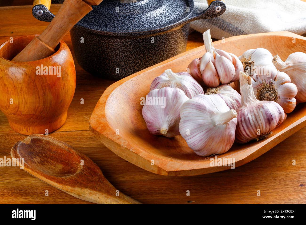 Close Up Raw, frische Knoblauchzehen und Zwiebeln auf rustikalem Holztisch mit Schüssel. Vorderansicht Stockfoto