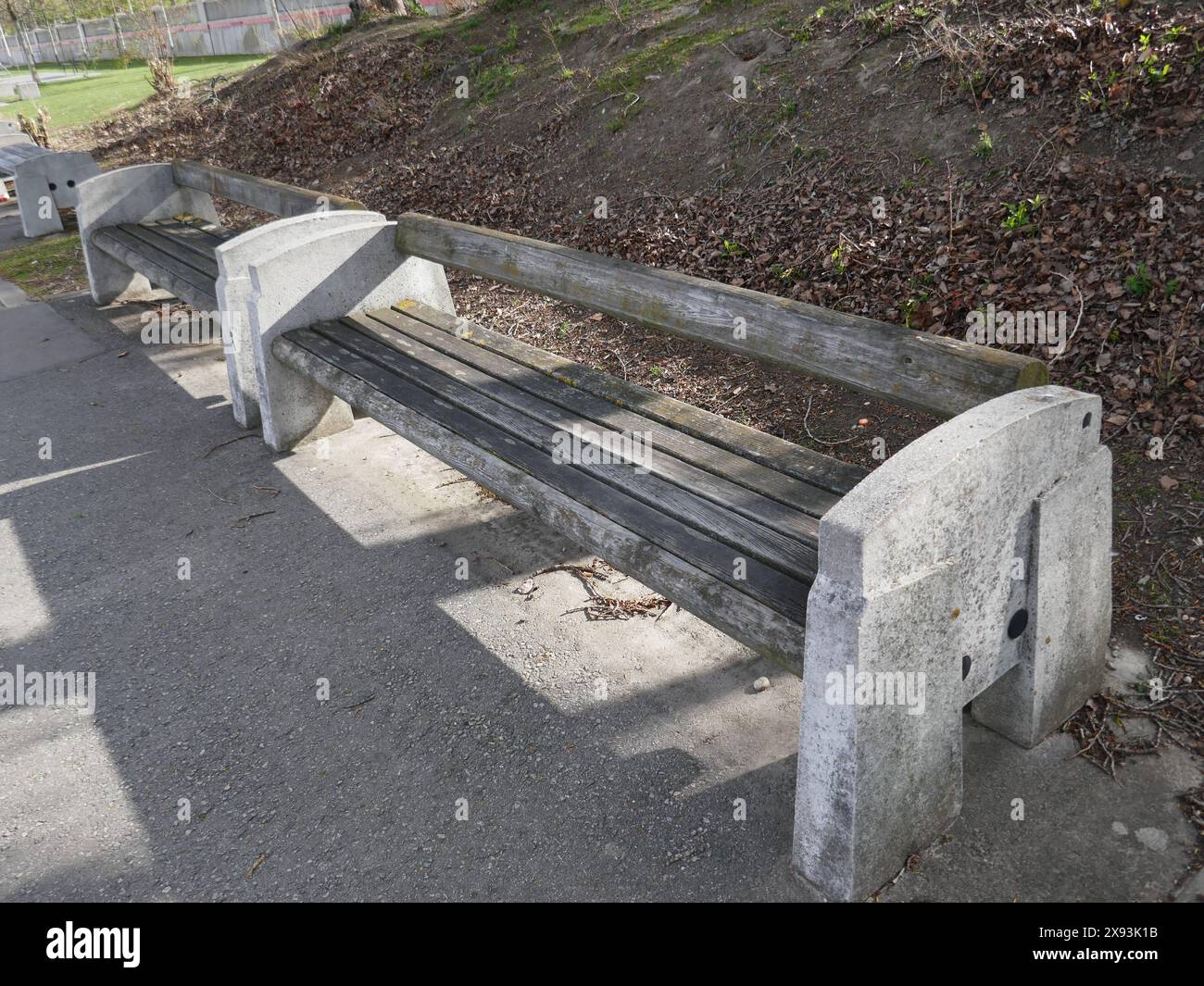 Parkbank aus Holz und Beton in modernem Stil entlang des Gehwegs Stockfoto