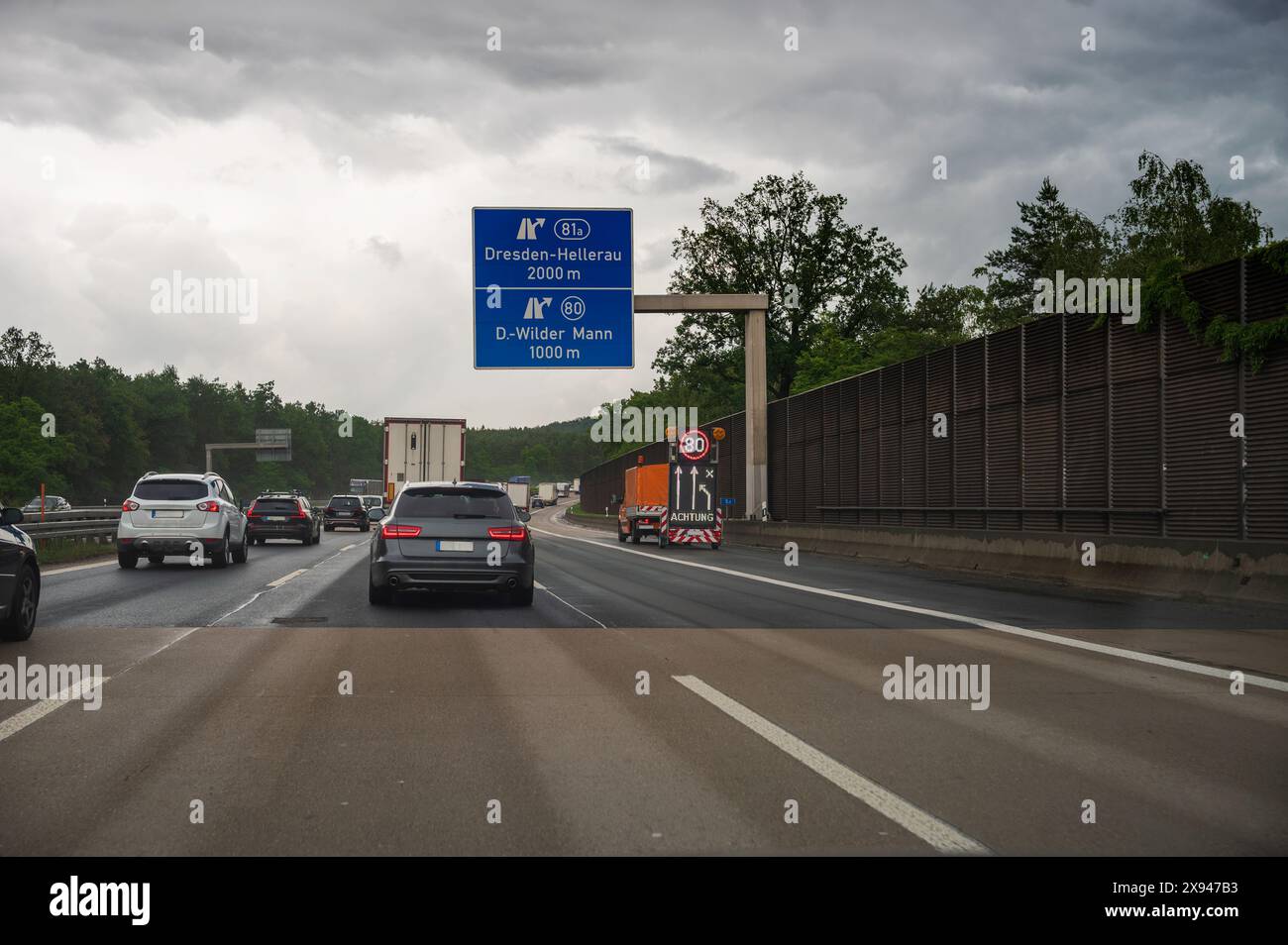 Ein Baustellenfahrzeug auf der Autobahn mit einem Schild, das eine Geschwindigkeitsbegrenzung anzeigt Stockfoto