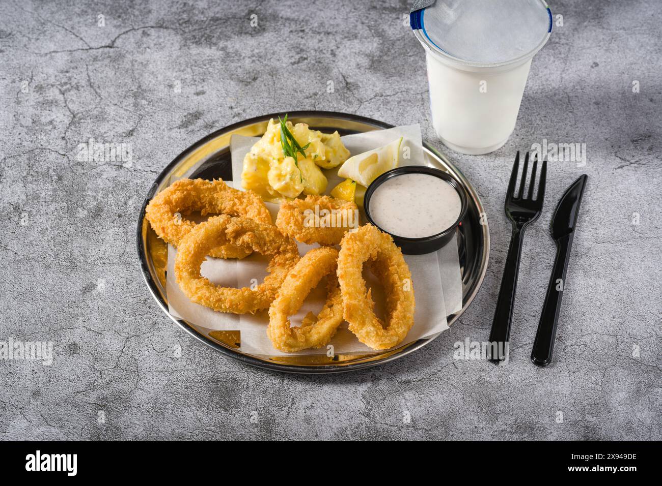 Gebratene Calamari mit Kartoffelsalat daneben auf Steintisch Stockfoto