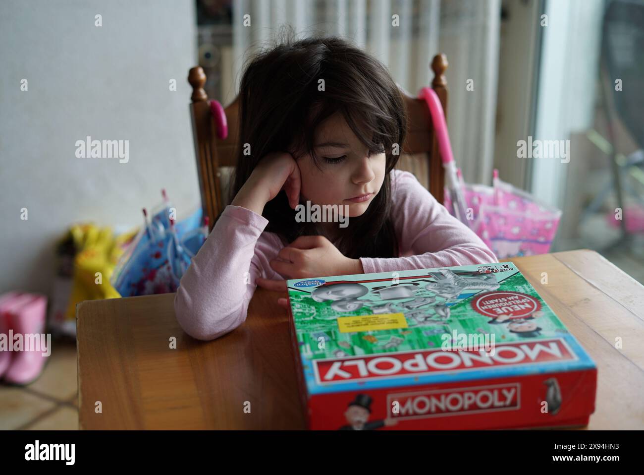 Iserlohn, NRW, Deutschland. August 2023. Isolation at the Game Table: Ein dunkelhaariges Girl's Lonely Monopoly Game Stockfoto