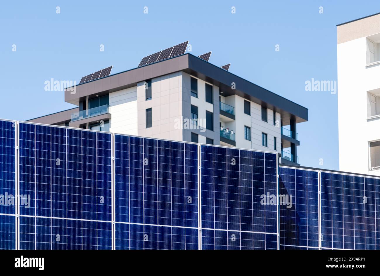 Solarpaneele versorgen Wohngebäude in der Stadt mit Strom. Nachhaltigkeit und grüne Energie in der modernen Stadt. Stockfoto