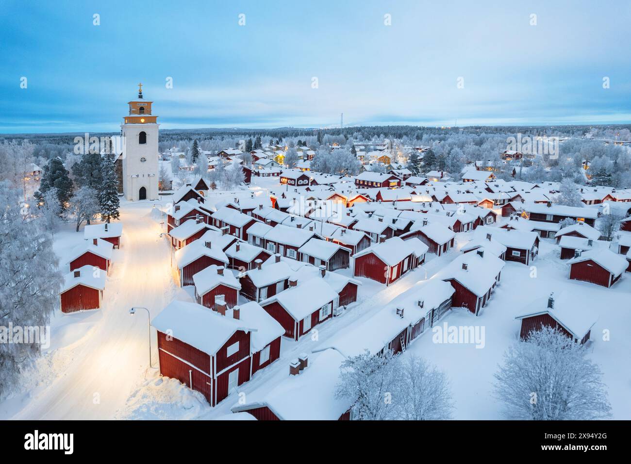 Aus der Vogelperspektive auf das alte beleuchtete Gammelstad, bedeckt mit Schnee, mit roten Hütten rund um die Kirche, Gammelstad Church Town, UNESCO, Schweden Stockfoto