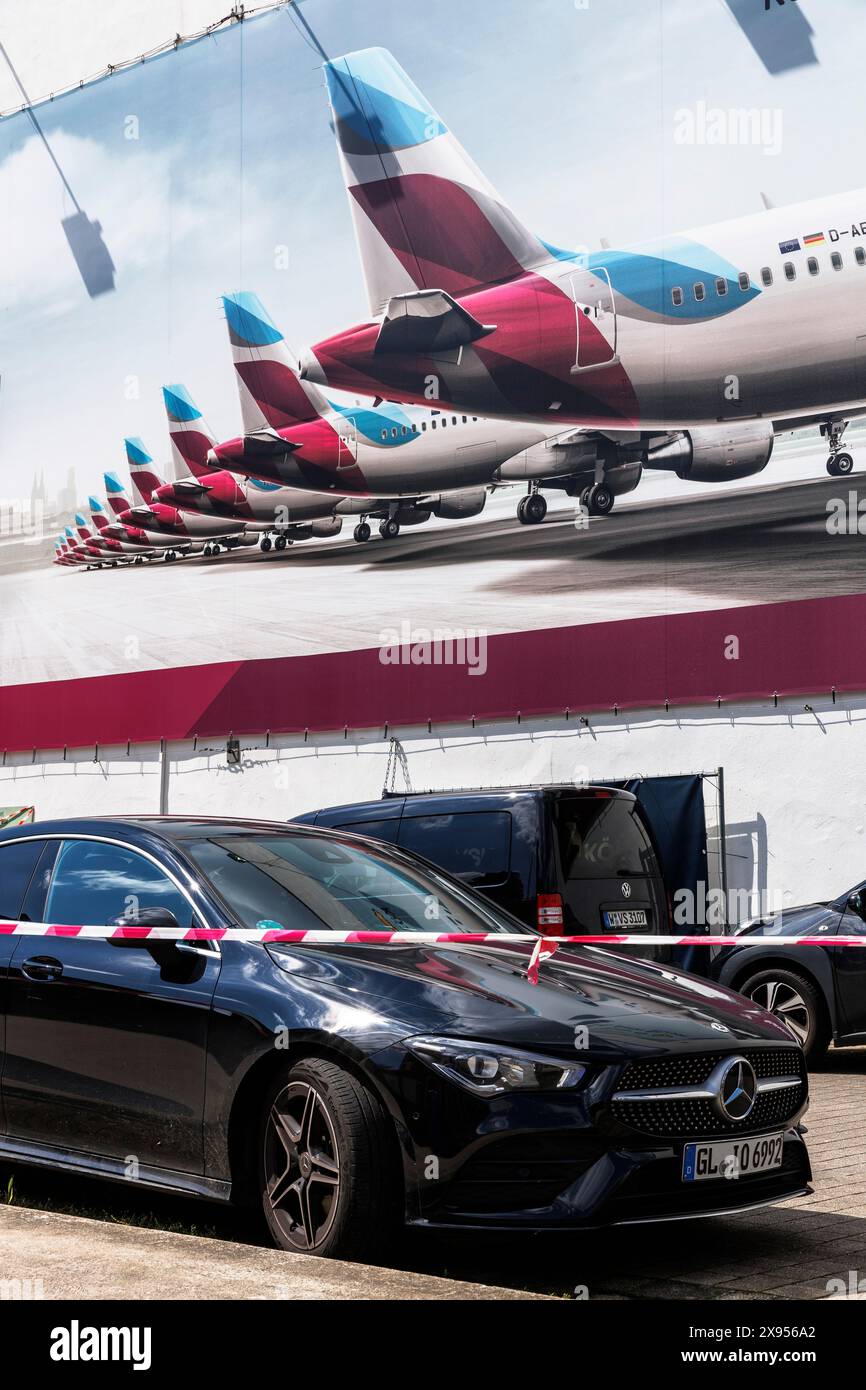 Geparkte Autos vor einer großen Werbetafel der Fluggesellschaft im Kölner Stadtteil Müelheim. Geparkte Autos vor einem großen Werbeplakat einer Grippe Stockfoto