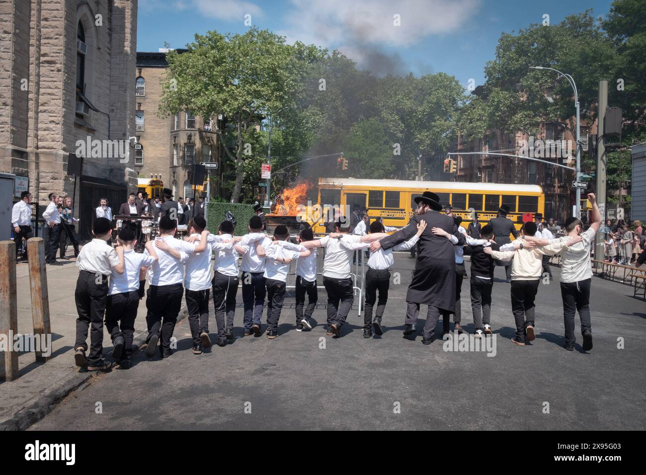 Während der lag-Bomer-Feierlichkeiten 2024 tanzen ein Rabbiner und seine Schüler in Richtung des traditionellen Feuers. In Brooklyn, New York. Stockfoto