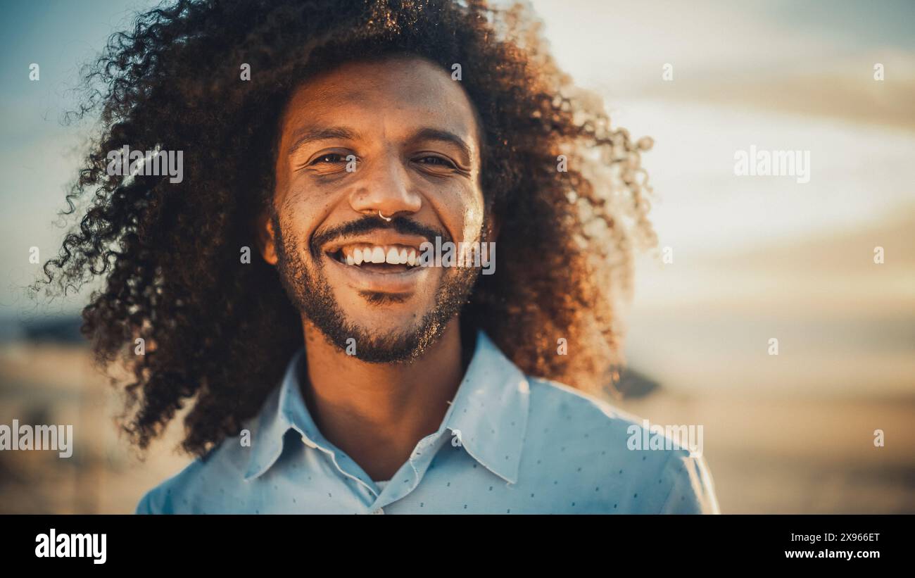 Porträt eines glücklichen jungen Erwachsenen männlich mit Afro-Haar- und Nasenring-Piercing posiert für die Kamera. Hübsche, Vielseitige, Multiethnische Schwarze, Die Lächelnd Sind. Warme Farbbearbeitung. Stockfoto