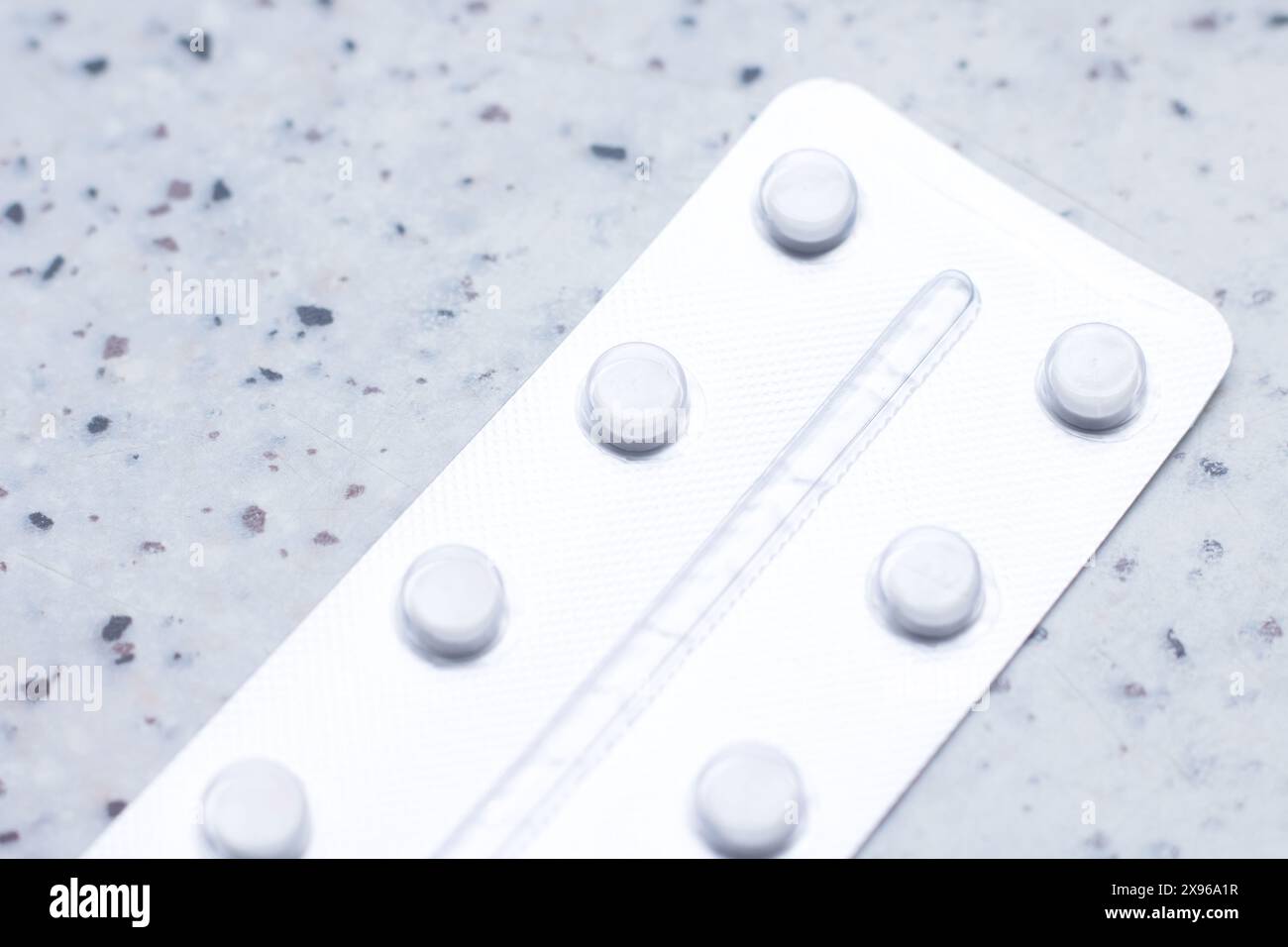 Eine rechteckige Blisterpackung Pillen mit einem Kreismuster in Elektroblau auf einer Plastikhülle. Es sitzt auf einer Metallplatte, ähnlich einem Moden Stockfoto